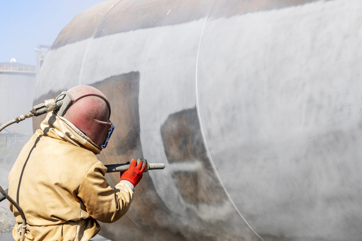 Close up view of sandblasting before coating. Abrasive blasting, more commonly known as sandblasting, is the operation of forcibly propelling a stream of abrasive material against a surface.