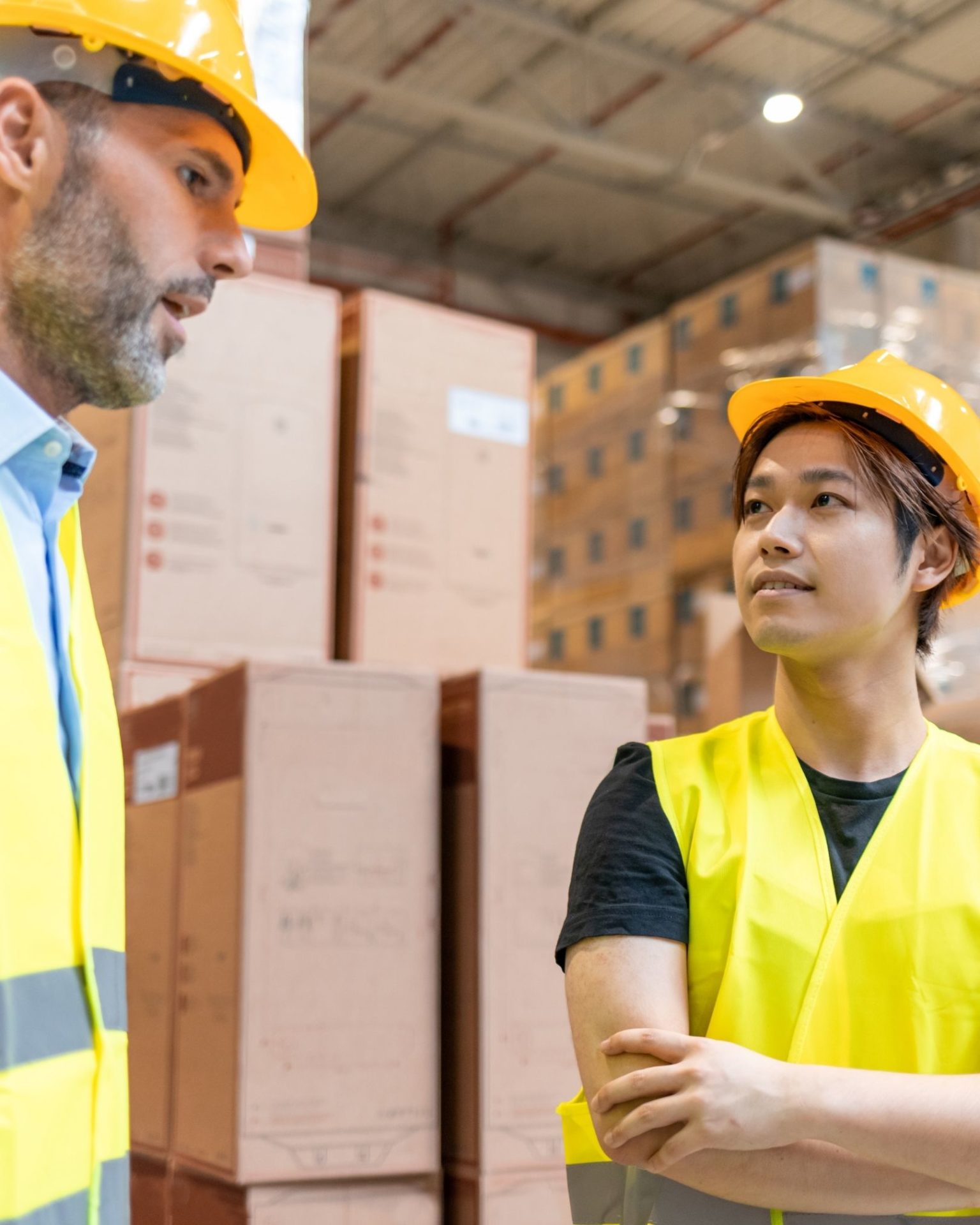 Two industrial workers wearing safety gear and examining heavy machinery