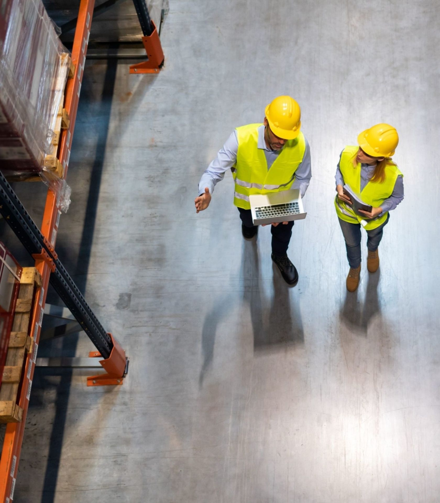 Two industrial workers wearing safety gear and examining heavy machinery