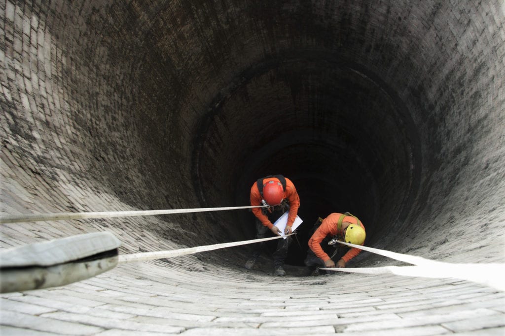 two men in large well with deceleration ppe