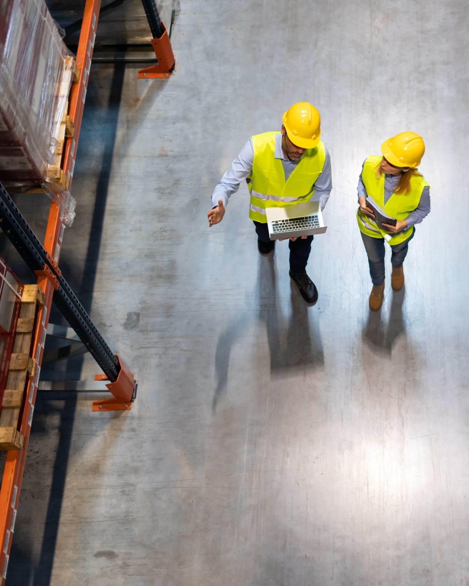Policy Development AST Two industrial workers wearing safety gear and examining heavy machinery
